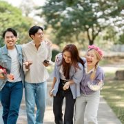 Diverse group of friends laughing and walking together in a park.