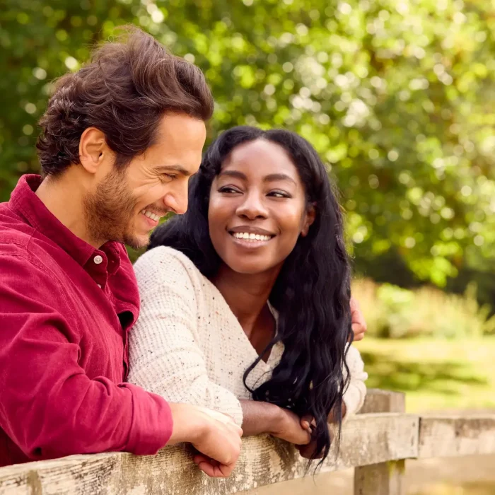Loving Mixed Race Couple Leaning On Fence On Walk In Countryside