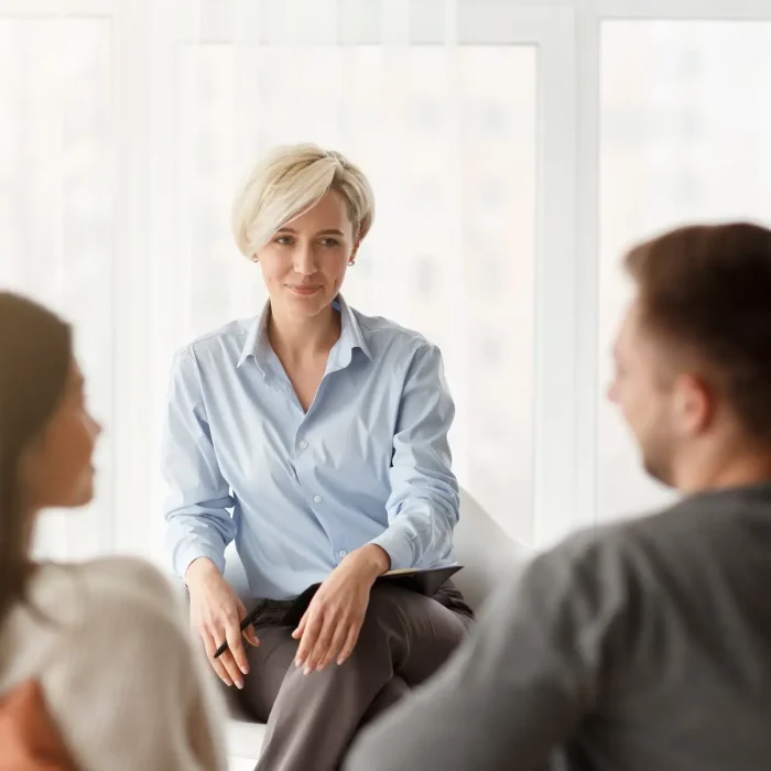 Psychologist Smiling Looking At Couple's Reconciliation Sitting In Office
