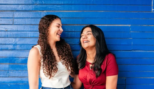 Two Hispanic friends with brackets laughing together