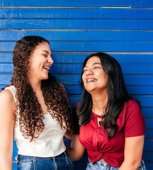 Two Hispanic friends with brackets laughing together
